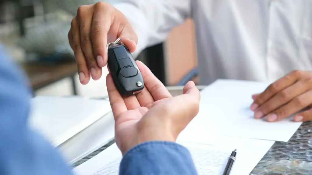 Homme d'affaires donnant la clé de la voiture et signant un accord de prêt au client.