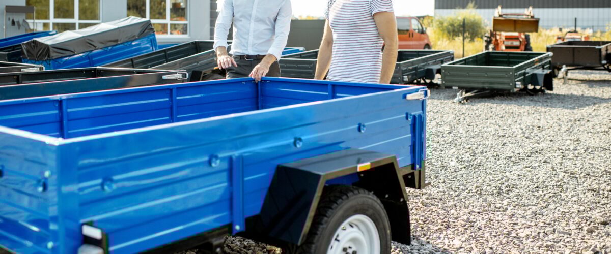 Agronome avec Salesman Choisant une nouvelle remorque de camion de ferme, debout sur le terrain ouvert de la boutique agricole