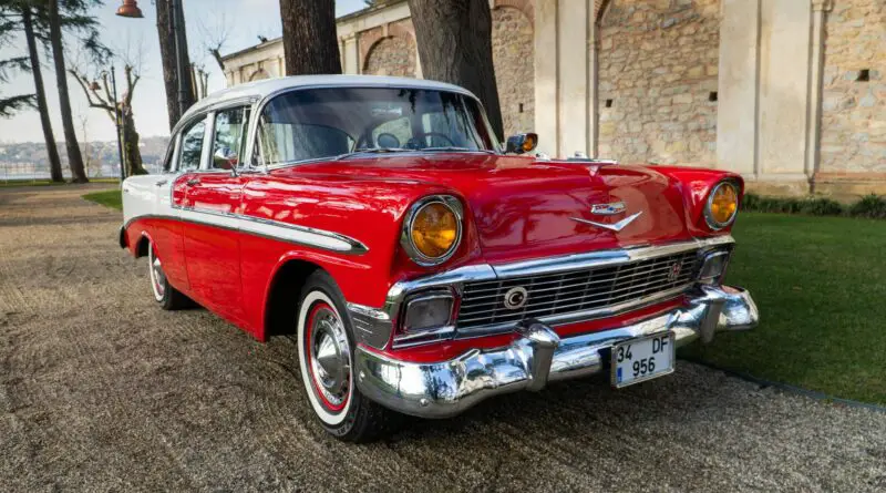 Une voiture Vintage rouge classique magnifiquement restaurée garée dans un cadre extérieur élégant, dégageant un charme intemporel.