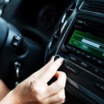 Image recadrée d'une femme tournant à la main de la radio en voiture