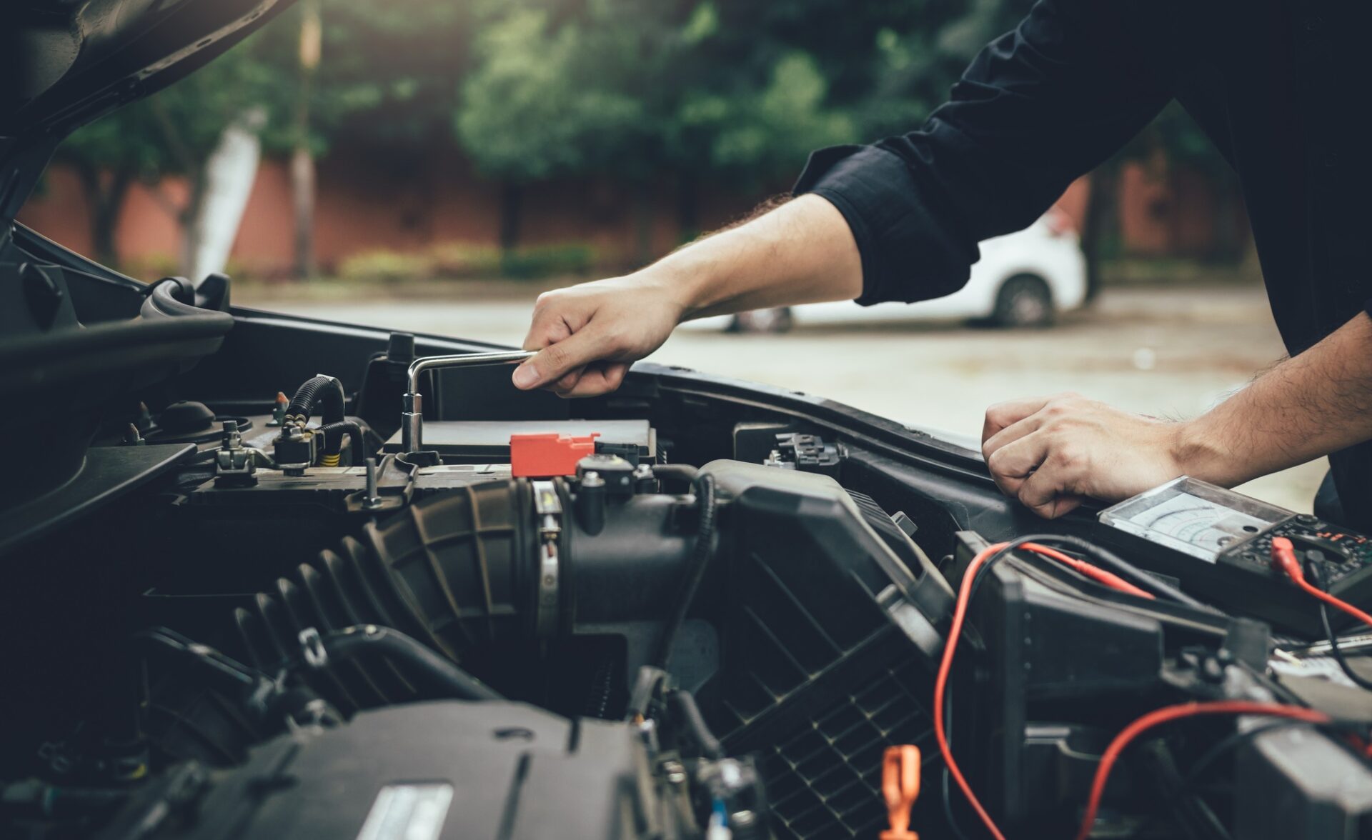 Le mécanicien de voiture vérifie le moteur et maintient la jauge de batterie.