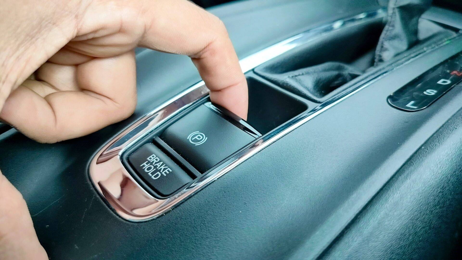 Le doigt appuyant sur le bouton de frein de stationnement électronique sur la voiture de luxe. 