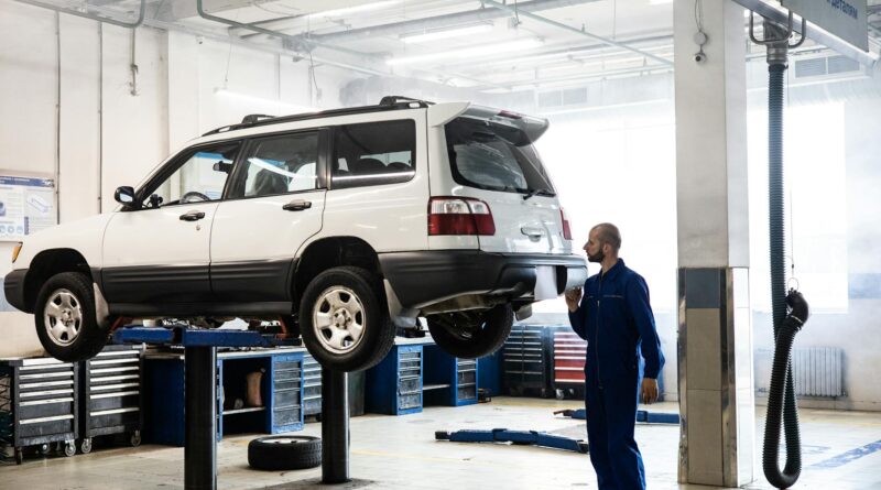 Mécanique inspectant un SUV levé dans un garage de réparation automobile moderne.